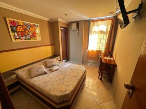 a bedroom with a bed and a table and a window at Grande Hotel in Duque de Caxias