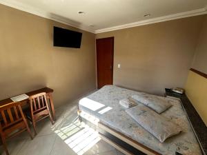 a bedroom with a bed and a television on the wall at Grande Hotel in Duque de Caxias