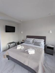 a white bedroom with a large bed with towels on it at Harmony Sunset in Skala Sotiros