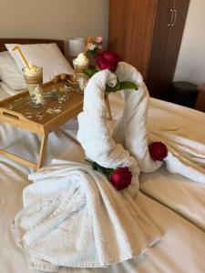 a bed with two towels and a table with roses at Balkan 024 in Subotica