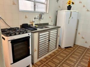 a kitchen with a stove and a sink and a refrigerator at Apartamento Brisa Do Mar em Peruíbe in Peruíbe