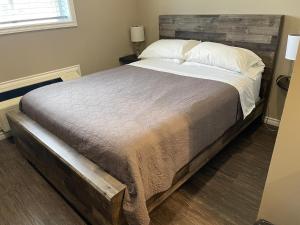 a bedroom with a large bed with a wooden headboard at Timber Wolf Inn Motel in Nipigon