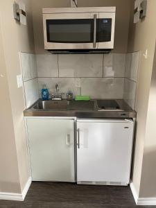 a kitchen with a sink and a microwave at Timber Wolf Inn Motel in Nipigon