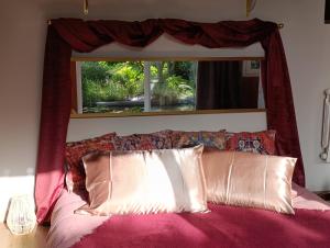 a bed with a red head board with a window at La suite mahradja in Quimper