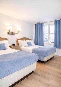 two beds in a hotel room with blue curtains at Cape Harbor Motor Inn in Cape May +22 photos