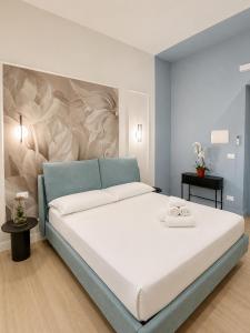 a bedroom with a large white bed with a blue headboard at Xenia Suites Duomo in Reggio di Calabria