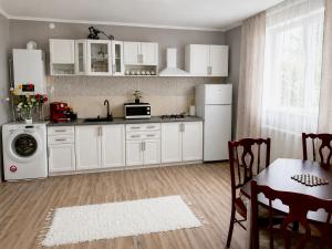 a kitchen with white cabinets and a table and a refrigerator at Casa Stefi in Copăceni