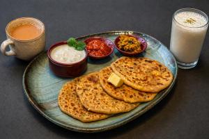 a plate of food with bread and dip and two glasses of milk at Hotel Montanaa Plaza Near Delhi Airport - Free Airport Pickup & Drop and Breakfast- Dinner complementary in New Delhi