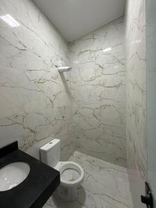 a bathroom with a white toilet and a sink at Casa Cor in Aruanã