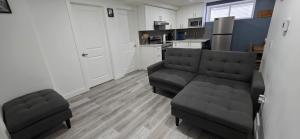 a living room with two chairs and a couch and a kitchen at Entire guest basement suite in Cochrane, AB in Cochrane