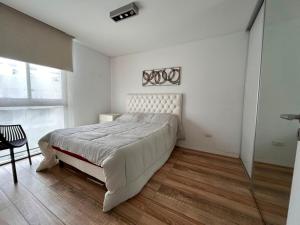 a white bedroom with a large bed and a chair at Emma in Villa Carlos Paz