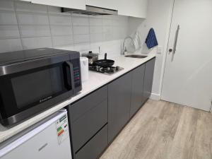 a small kitchen with a microwave and a stove at Kingsley at 1 on Albert in Cape Town