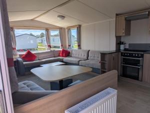a living room with a couch and a table in a caravan at 69 Lighthouse View, Silver Sands Holiday Park in Lossiemouth