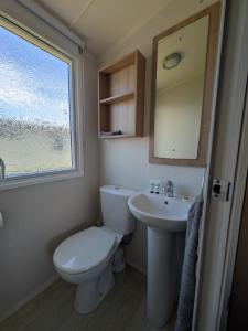 a bathroom with a toilet and a sink and a window at 69 Lighthouse View, Silver Sands Holiday Park in Lossiemouth +14 photos