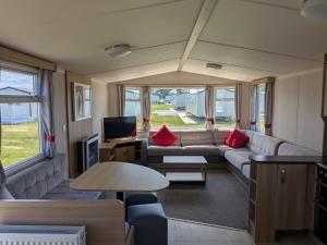 a living room with a couch and a tv in a caravan at 69 Lighthouse View, Silver Sands Holiday Park in Lossiemouth
