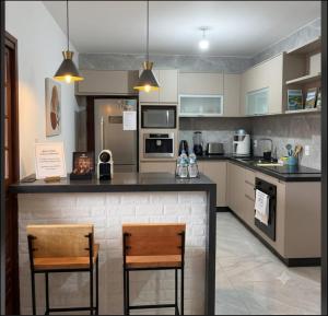 a kitchen with two chairs and a counter top at Casa com piscina e área gourmet próximo à praia com quarto suíte privativo in Saquarema