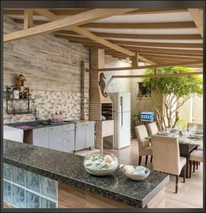 a kitchen with a counter and a table with chairs at Casa com piscina e área gourmet próximo à praia com quarto suíte privativo in Saquarema