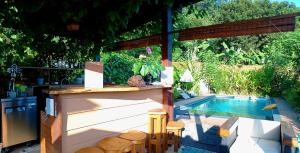 a backyard with a pool and a bar with a table and chairs at Fare Atihau Vairao in Matiti
