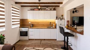 a small kitchen with white cabinets and a black chair at Apaurin Lodge - Peacful Nature Escape near Bosnian Pyramids in Visoko