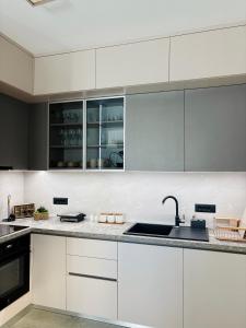a kitchen with white cabinets and a sink at Villa Deromano in Šušanj