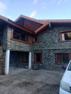 a stone house with a car parked in front of it at Aurum patagonia hotel in Lago Puelo