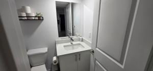a white bathroom with a sink and a mirror at Entire guest basement suite in Cochrane, AB in Cochrane +24 photos