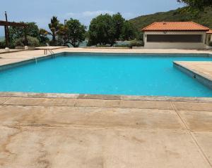 a blue swimming pool with a building in the background at Beachfront Ocean View Loft with Beach, Pool and Parking in Portmore