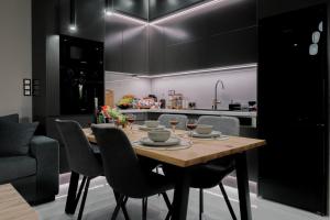 a dining room table with chairs and a kitchen at Anemos Suites Loutraki in Loutraki