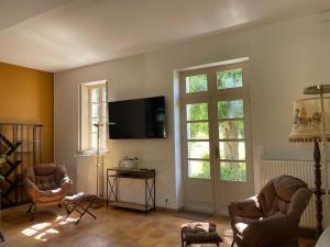 a living room with two chairs and a flat screen tv at La Raimbauderie, villa 4 étoiles, avec clim, au coeur de la nature et des vignobles in La Chapelle-Montlinard
