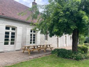a wooden picnic table next to a tree in front of a building at La Raimbauderie, villa 4 étoiles, avec clim, au coeur de la nature et des vignobles in La Chapelle-Montlinard