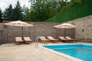 a pool with chairs and umbrellas next to a wall at Villa Royalstone in Donja Ralja