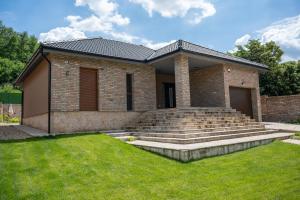 a brick house with stairs and a grass yard at Villa Royalstone in Donja Ralja
