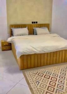 a bedroom with a large bed with white sheets and a rug at Appart lotus in Cocody