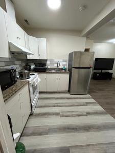 a kitchen with white cabinets and a stainless steel refrigerator at Lower Suite- 10 minutes away from airport in Calgary