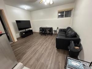 a living room with a black couch and a television at Lower Suite- 10 minutes away from airport in Calgary