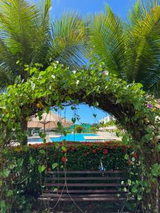 a bench in front of a beach with flowers at Lindo apartamento em Muro Alto, Porto de Galinhas, Vista para as piscinas, 3 qtos e sala climatizados, Acomoda até 8 pessoas in Ipojuca