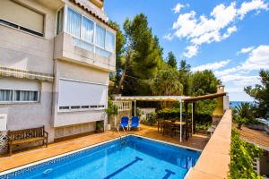a swimming pool in front of a house with a table and chairs at Buda Villa Planetcostadorada in Salou