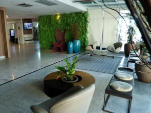a lobby with a green wall with chairs and a table at Hotel Beira Mar Boa Viagem By Flatbpaiva in Recife