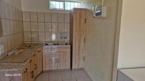 a small kitchen with wooden cabinets and a sink at Self Contained Batchelor pad in Germiston