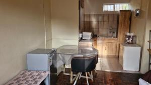 a small kitchen with a table and a refrigerator at Self Contained Batchelor pad in Germiston