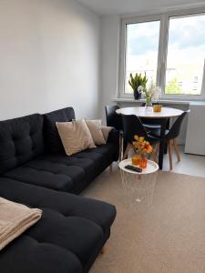 a living room with a black couch and a table at Apartament w Centrum Miasta in Brodnica