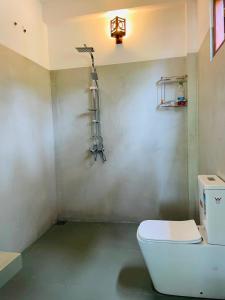 a bathroom with a toilet and a light on the wall at Villa Serandiva in Galle