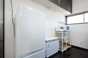 a kitchen with a refrigerator and a microwave at Shiokaze Miura Kaigan - 三浦海岸 in Miura