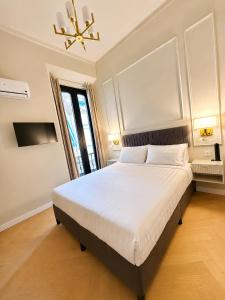 a bedroom with a large white bed with a chandelier at Malaga Rooms in Málaga