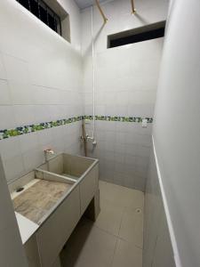 a white tiled bathroom with a sink and a shower at Casa de Libre Independencia in Mocoa