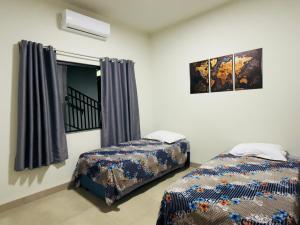 a bedroom with two beds and a window at Apartamento minutos do centro in Sinop