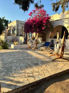 a patio with two hammocks and a tree with pink flowers at 7Olives Emerald Boutique Apartment in Kastraki