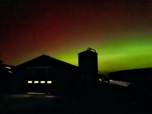 an aurora shines in the sky behind a building at Das Zimmer - Bauernhof-Nordsee-Urlaub in Norderfriedrichskoog
