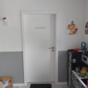 a white door with a sign on it in a kitchen at Das Zimmer - Bauernhof-Nordsee-Urlaub in Norderfriedrichskoog