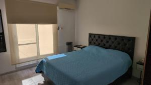 a bedroom with a bed with a blue comforter and a window at Renzo in Deán Funes